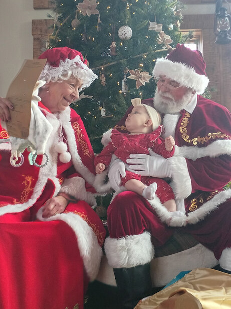 Santa and Mrs. Claus holding a baby at True Scale USA